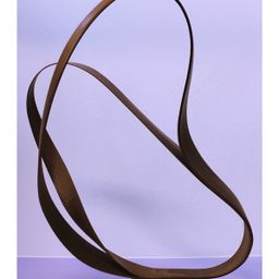 Eine abstrakte Skulptur mit brauner, welliger Textur steht vor einem lila Hintergrund. Die Skulptur hat ein fließendes, geschwungenes Design.