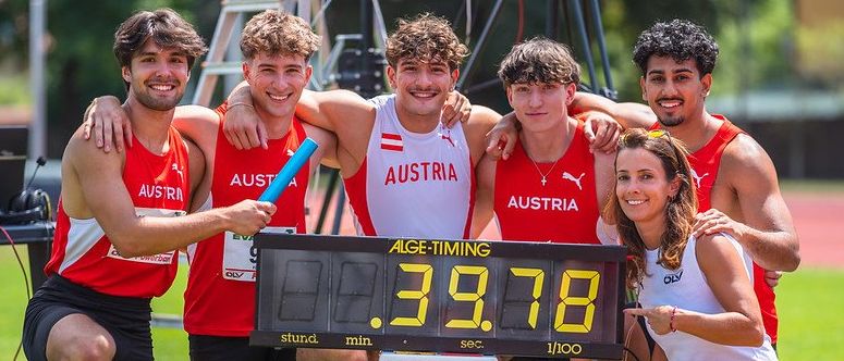 Sechs Athleten posieren für ein Foto bei einem Leichtathletik-Event, lächelnd und halten eine Staffel. Die digitale Uhr zeigt 39,78 Sekunden an. Sie tragen rote und weiße Trikots mit dem Aufdruck Österreich.