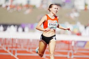 Eine Athletin läuft bei einem Leichtathletikwettbewerb in einer orangefarbenen Trikotjacke mit dem Namen Engel und der Nummer 6 auf den Shorts.