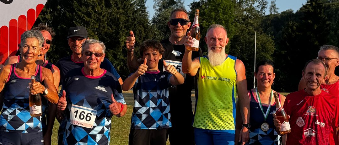 Eine Gruppe von Läufern, alle in passender blauer und schwarzer Sportbekleidung gekleidet, stehen gemeinsam auf einer Laufbahn und lächeln, während sie Champagnerflaschen halten. Sie feiern ihren Erfolg, wobei ein Mann in der Mitte ein gelbes Shirt trägt und eine Flasche hält.