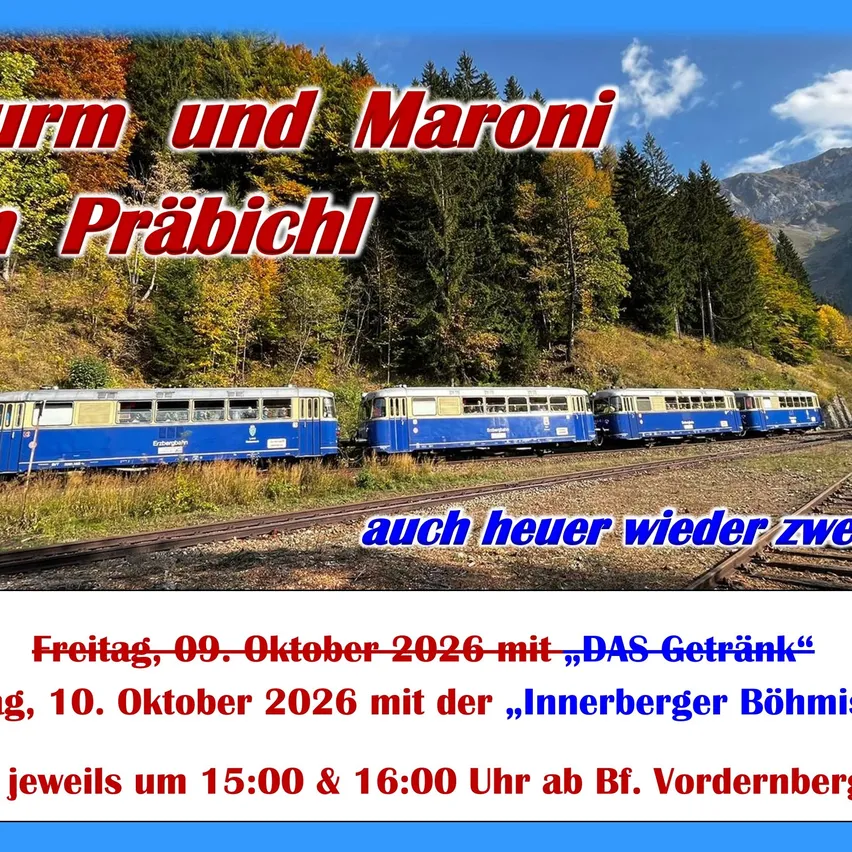 Ein blauer und weißer Zug befindet sich auf den Gleisen in einem Gebirgsgebiet.