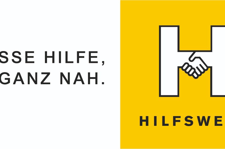 A yellow and white logo with the text 'SE HILFE, A ANZ NAH.' and a handshake symbol. The word 'HILFS' is in black on a yellow background.