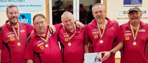 Fünf Männer in roten Trikots mit Medaillen posieren für ein Foto. Sie halten ein Papier mit einem Foto einer Frau. Hinter ihnen ist ein Banner mit den Worten "Sparkasse Neunkirchen".