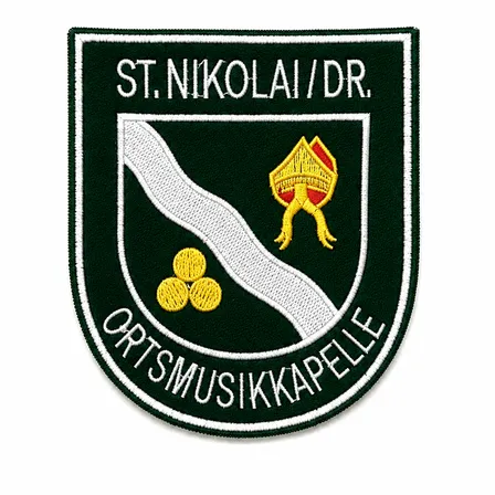 Gesticktes Emblem mit 'St. Nikolai/DR.' oben, einem roten und gelben Objekt darunter und 'ORTSMUSIKKAPELLE' am unteren Rand.
