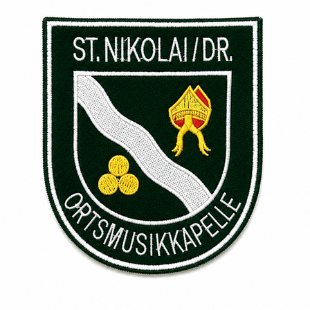 Gesticktes Emblem mit 'St. Nikolai/DR.' oben, einem roten und gelben Objekt darunter und 'ORTSMUSIKKAPELLE' am unteren Rand.