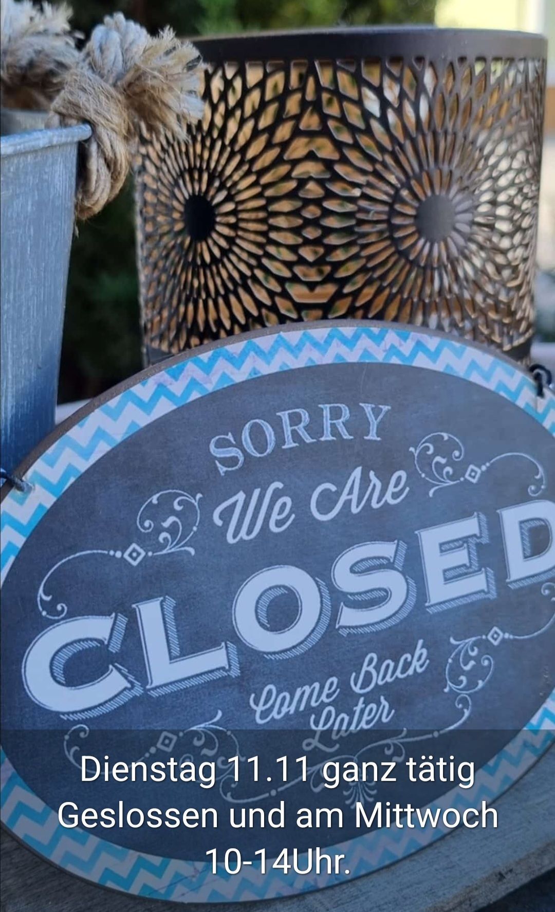 A signboard reads, 'Sorry, we are closed' with decorative borders. The background is blurred with decorative lanterns.