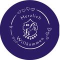 Rundes Logo mit violettem Hintergrund und weißem Pferd, umgeben von Herzen. Der Text lautet 'Herzlich Willkommen Zendorf'.