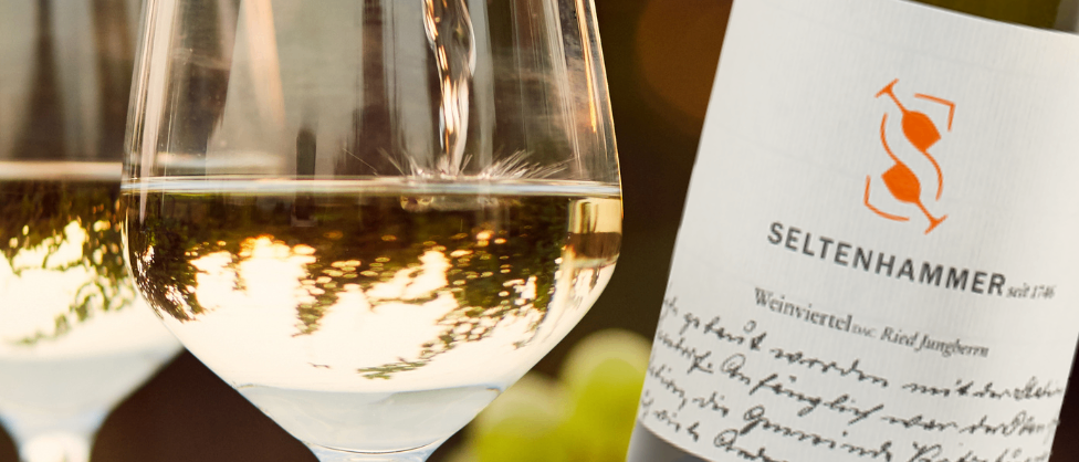 Ein Bild einer Flasche Seltenhammer-Wein, die in ein Weinglas gegossen wird. Das Weinglas ist zur Hälfte gefüllt.