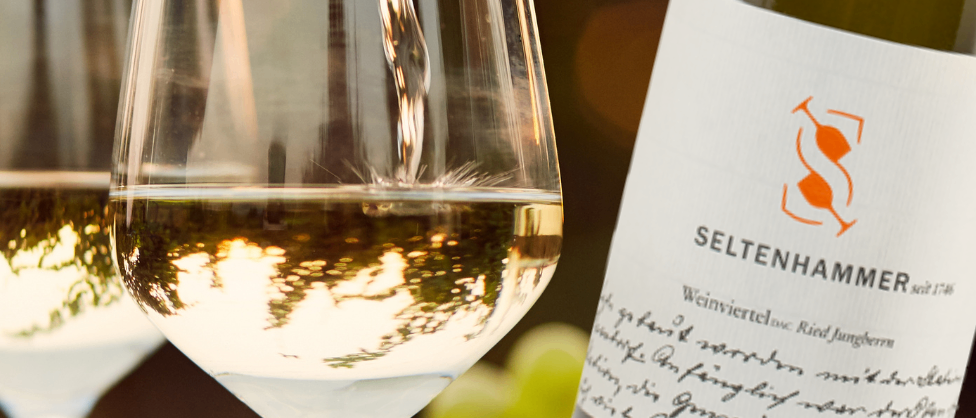 Ein Bild einer Flasche Seltenhammer-Wein, die in ein Weinglas gegossen wird. Das Weinglas ist zur Hälfte gefüllt.