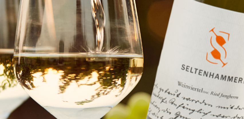 Ein Bild einer Flasche Seltenhammer-Wein, die in ein Weinglas gegossen wird. Das Weinglas ist zur Hälfte gefüllt.