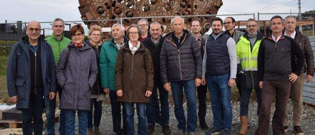 Eine Gruppe von Menschen posiert vor einem großen, alt aussehenden Bauwerk. Sie sind warm gekleidet und scheinen für ein Foto zu posieren.