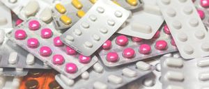 Ein Stapel verschiedener Medikamente, einschließlich weißer, gelber und rosa Pillen, einige in Blisterpackungen und andere in Kapseln, ordentlich gestapelt.