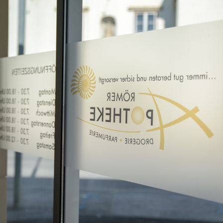 Eine Glastür zeigt ein Logo mit dem Text 'PHOENIX ELECTRIC' und einem goldenen Sonnendesign. Der Hintergrund ist verschwommen mit weißen und blauen Elementen.