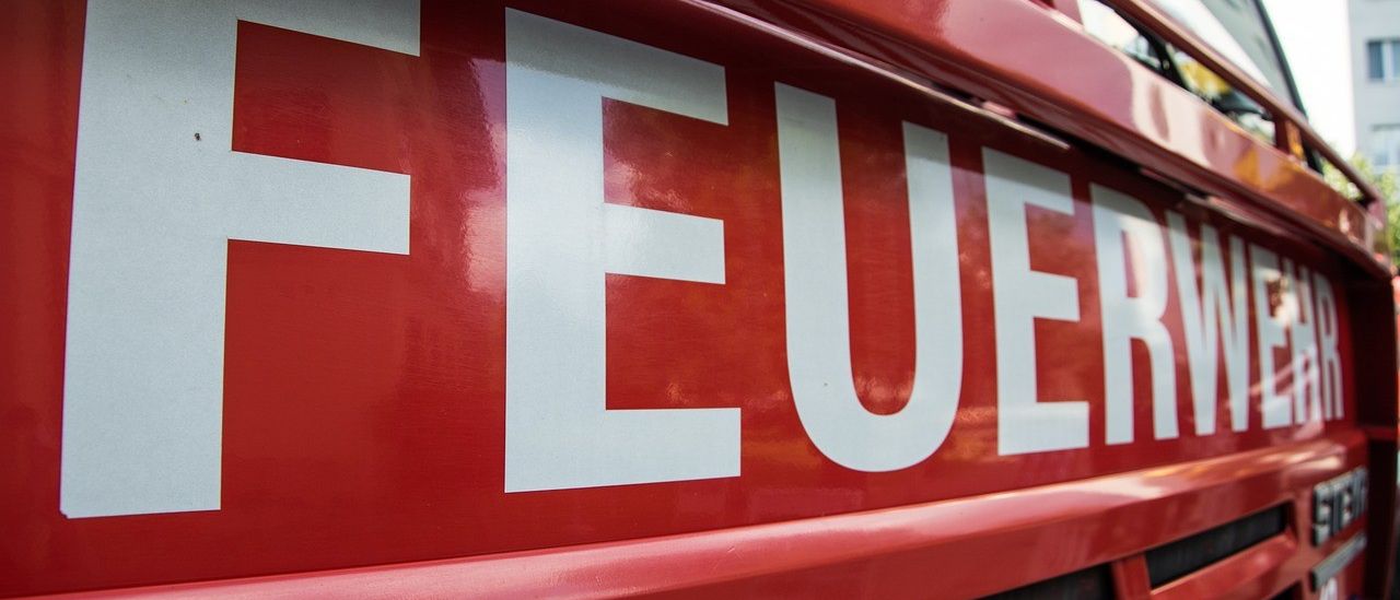 Eine Nahaufnahme eines roten Feuerwehrwagens mit dem Wort Feuer in Weiß auf seiner Seite geschrieben.