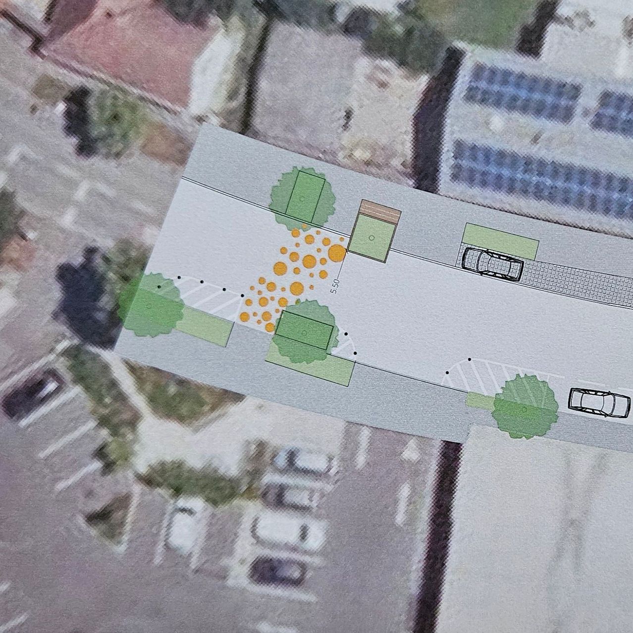 Aerial view of a neighborhood with a street layout, trees, and solar panels on a building.