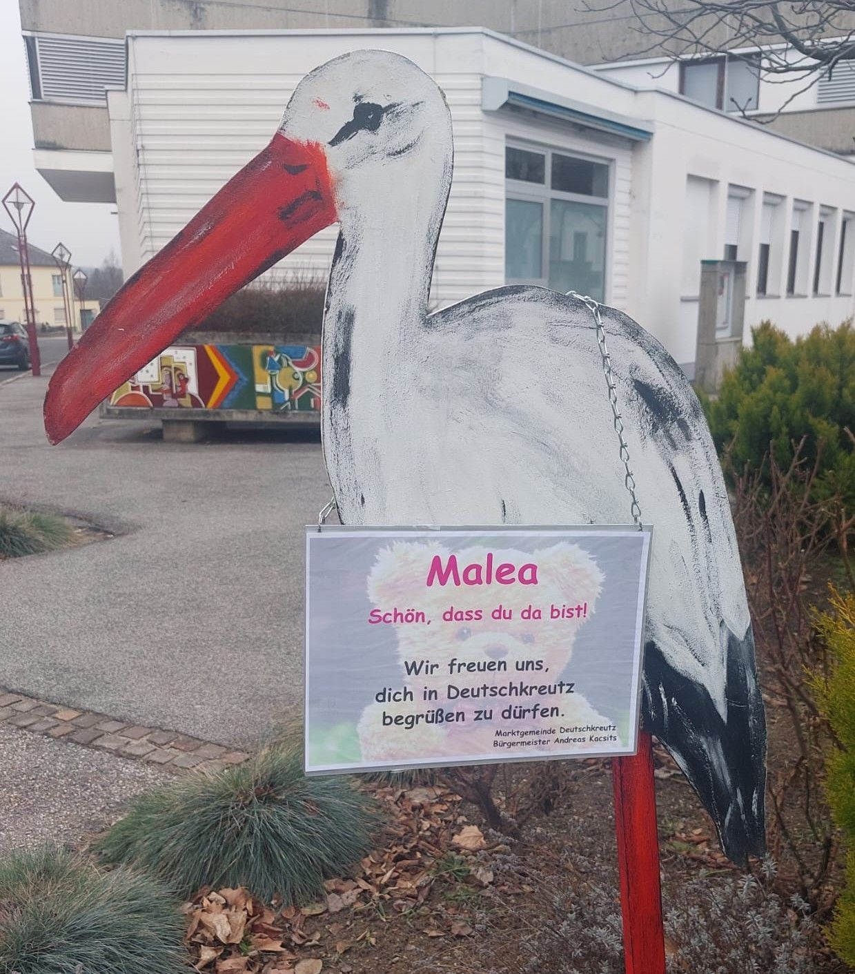 A painted stork with a sign reading 'Malea,' 'We are happy you are here,' and 'Germantown welcomes you' stands in front of a building.