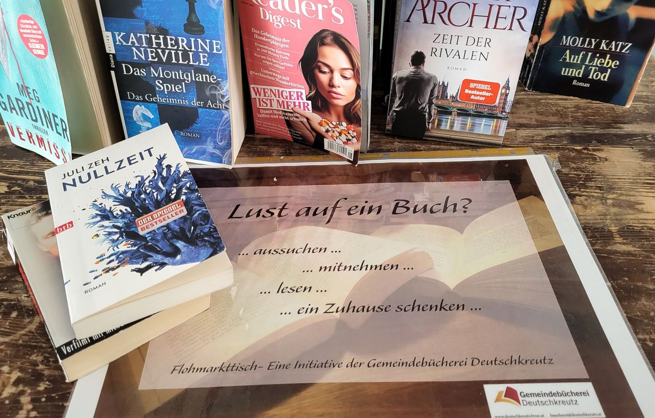 A selection of books, including 'Zeit der Rivalen', 'Der Spiegel Bestseller', and 'Weniger ist mehr', is displayed on a wooden surface. A sign reads, 'Lust auf ein Buch?'.