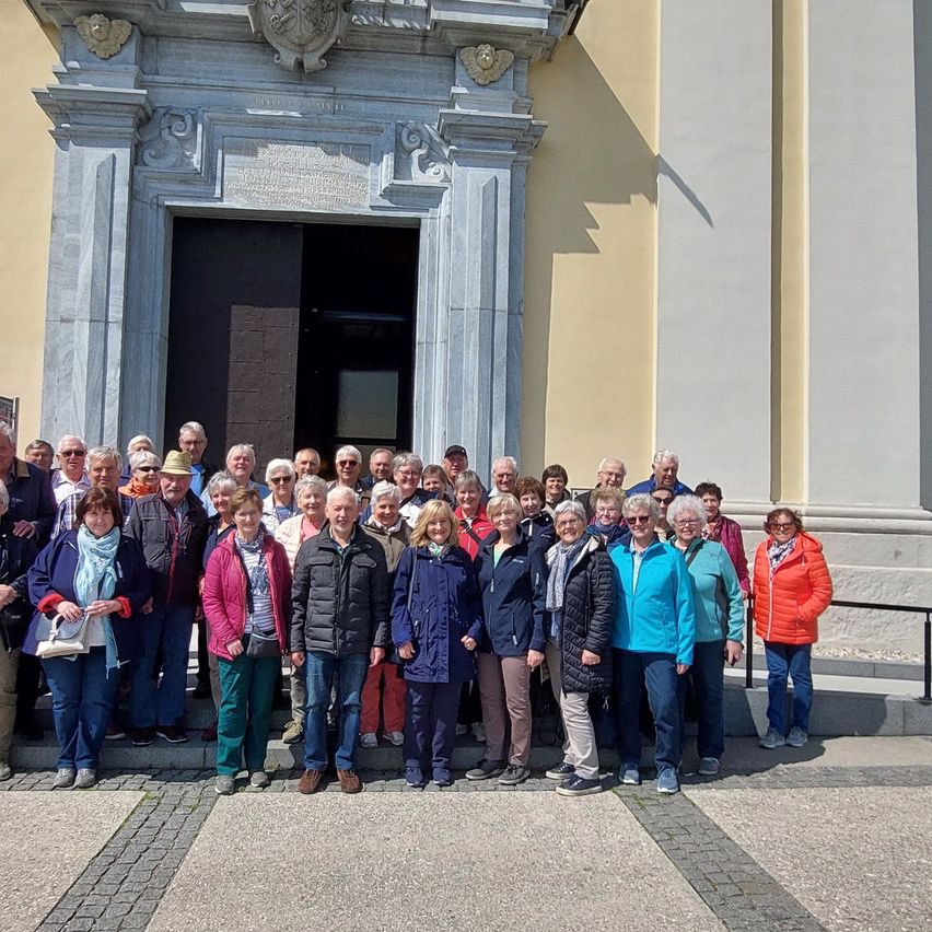 Eine große Gruppe von Menschen in verschiedenen Jacken und Mützen steht vor einem Gebäude.