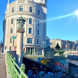 Eine Brücke mit Graffiti in der Nähe eines Gebäudes mit einer alten Laterne an einem sonnigen Tag.