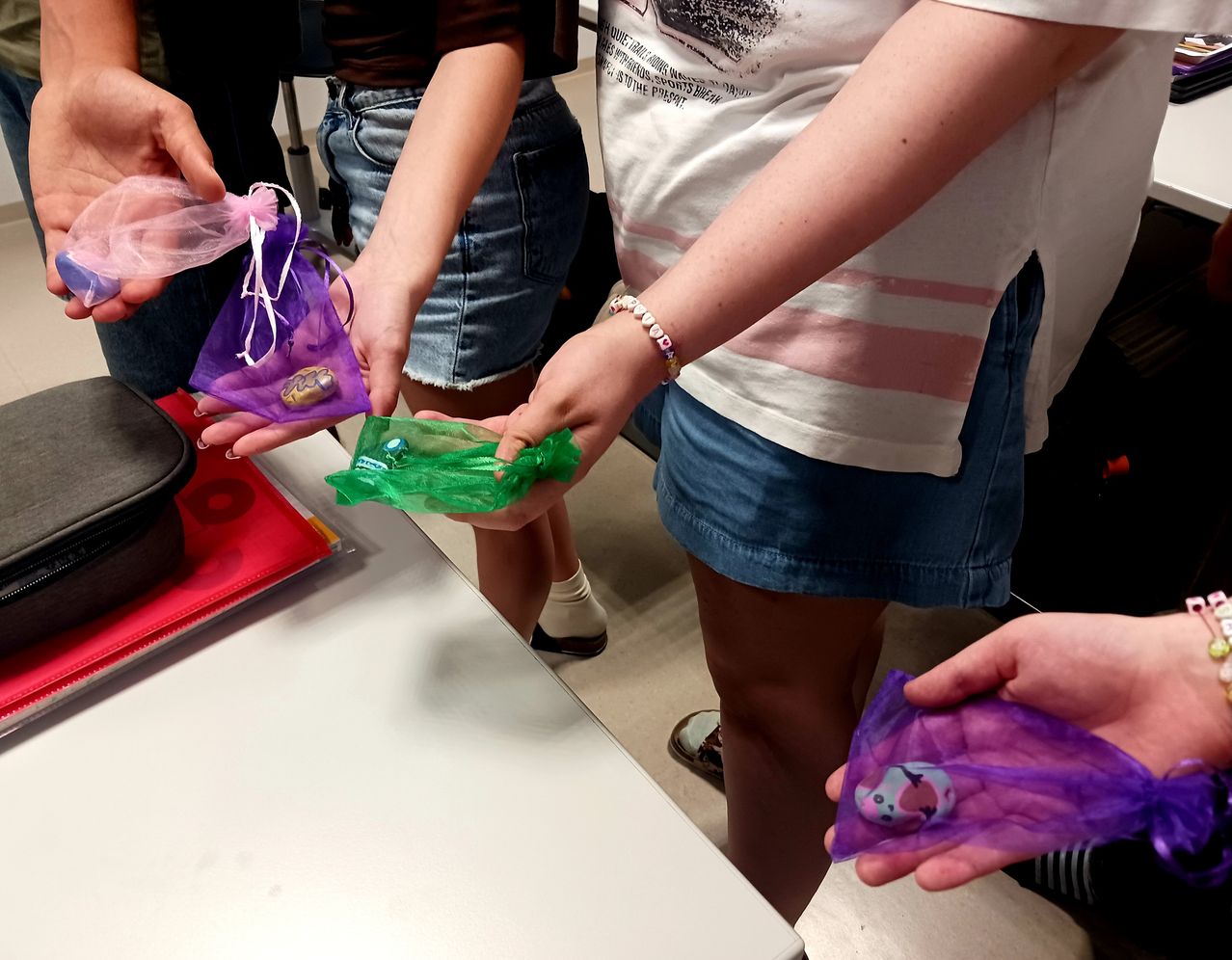 Mehrere Menschen halten kleine Plastiktüten mit Spielzeug darin, eine Person trägt ein Armband und eine andere ein Kleid.