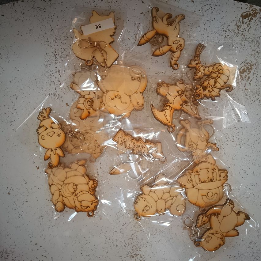 Multiple keychains of various cartoon characters are individually packaged in clear plastic bags. The keychains are light brown and have different poses and expressions.