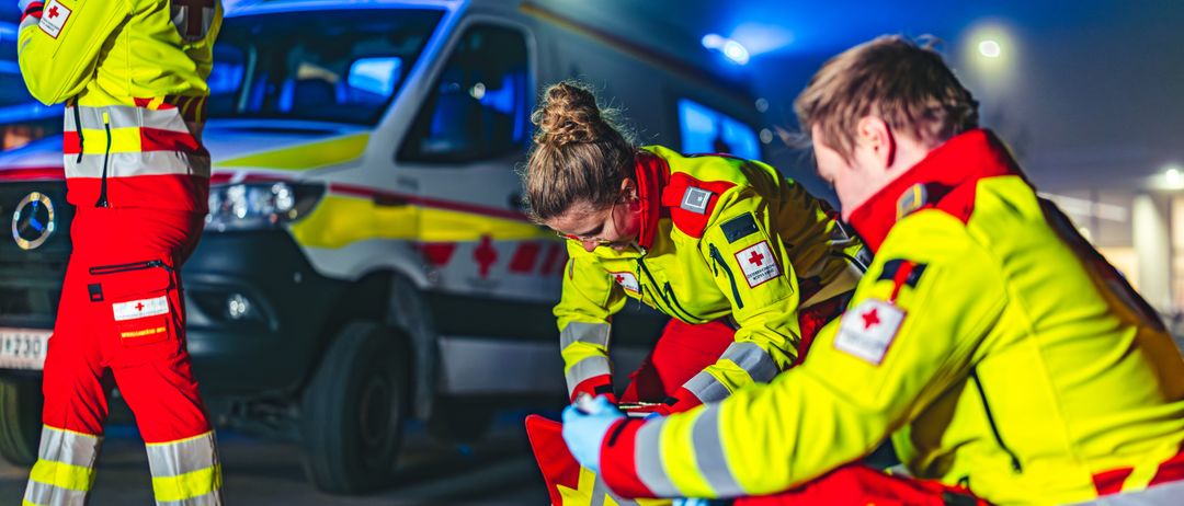 Notärzte versorgen nachts einen Verletzten, wobei ein Krankenwagen im Hintergrund zu sehen ist.