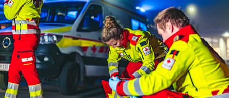 Notärzte versorgen nachts einen Verletzten, wobei ein Krankenwagen im Hintergrund zu sehen ist.