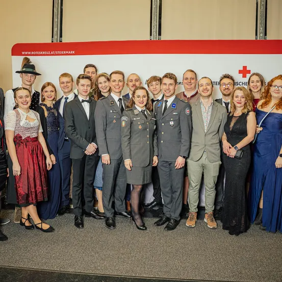 Eine Gruppe von Menschen in formeller Kleidung posiert für ein Foto vor einem Banner, möglicherweise bei einer Veranstaltung.