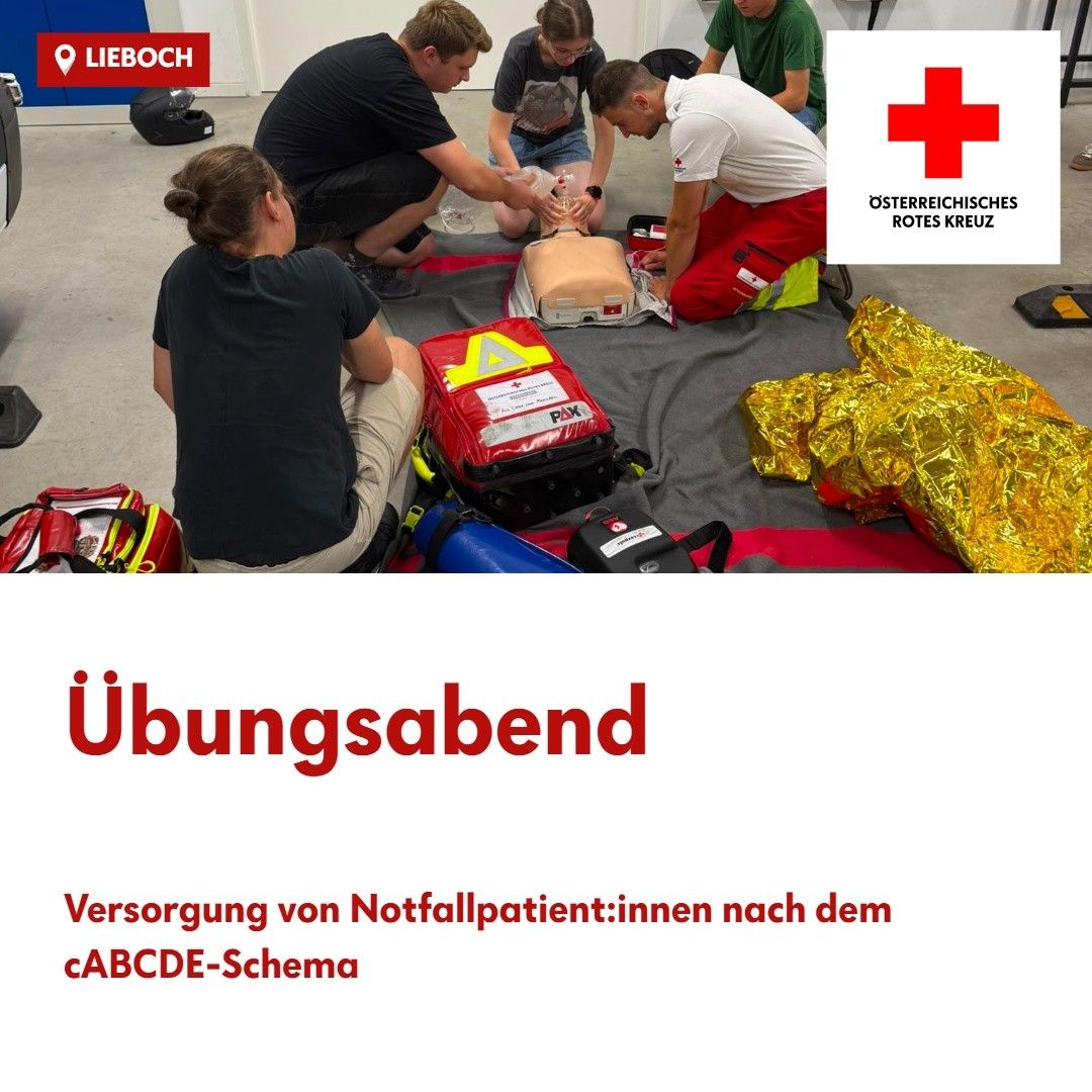 A group of people are practicing first aid on a dummy, with one person kneeling and another bending over. There are various emergency equipment and a red cross logo visible.