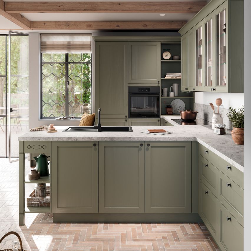 Eine moderne Küche mit grünen Schränken, einer Marmorarbeitsplatte, einem Waschbecken und einem Fenster mit Blick auf Bäume.