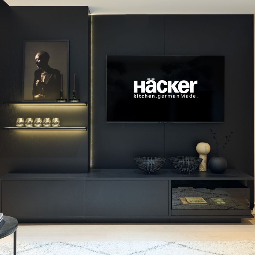 Ein modernes Wohnzimmer mit einer schwarzen Entertainment-Einheit, einem Flachbildfernseher, der die Marke Hacker anzeigt, und dekorativen Gegenständen wie Schalen und einem Fotorahmen.