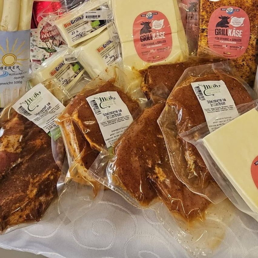 A closeup of assorted packaged foods, including grilled meat, cheese, and other items on a white tablecloth.