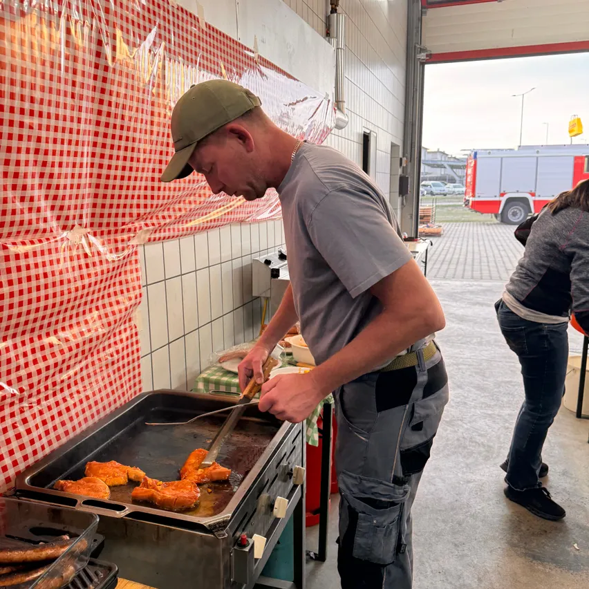 Ein Mann kocht Essen auf einem Grill in einer Garage.