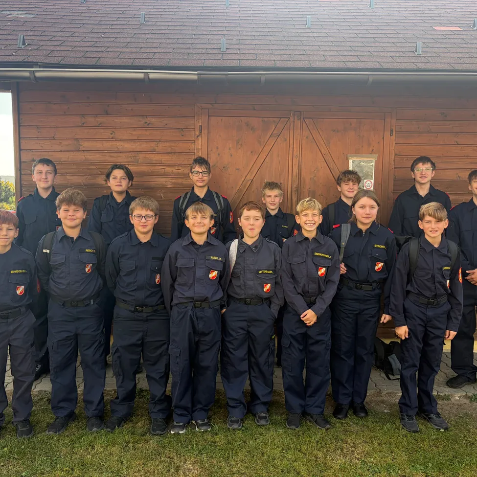 Eine Gruppe junger Männer in Uniform steht vor einem Holzgebäude.