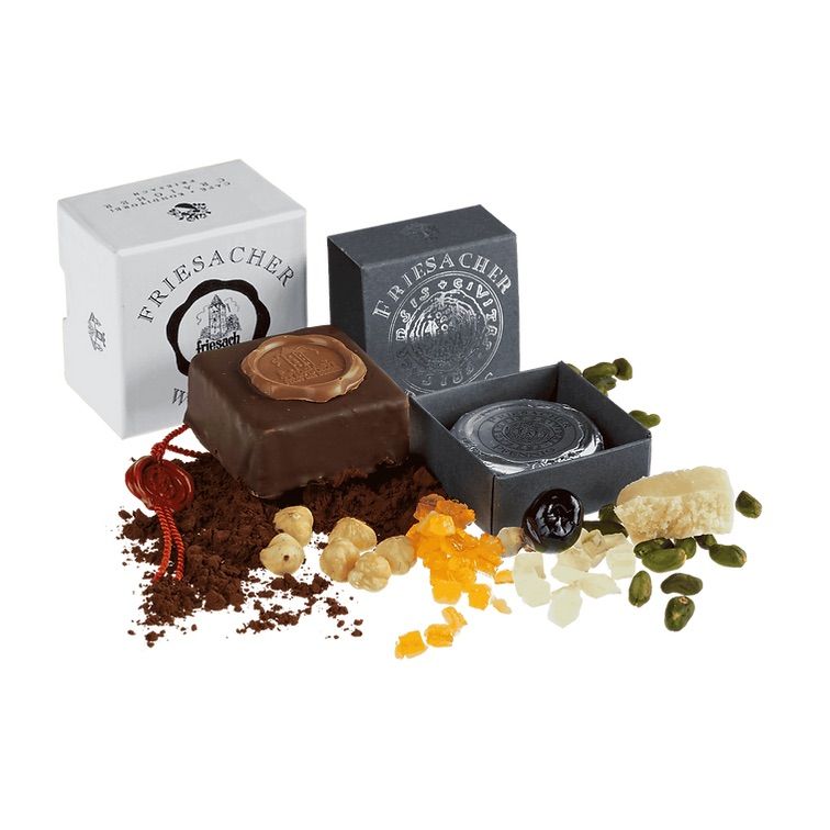 The image shows a variety of Friesaacher products, including chocolates, nuts, dried fruits, and other gourmet items, all neatly arranged on a white background.