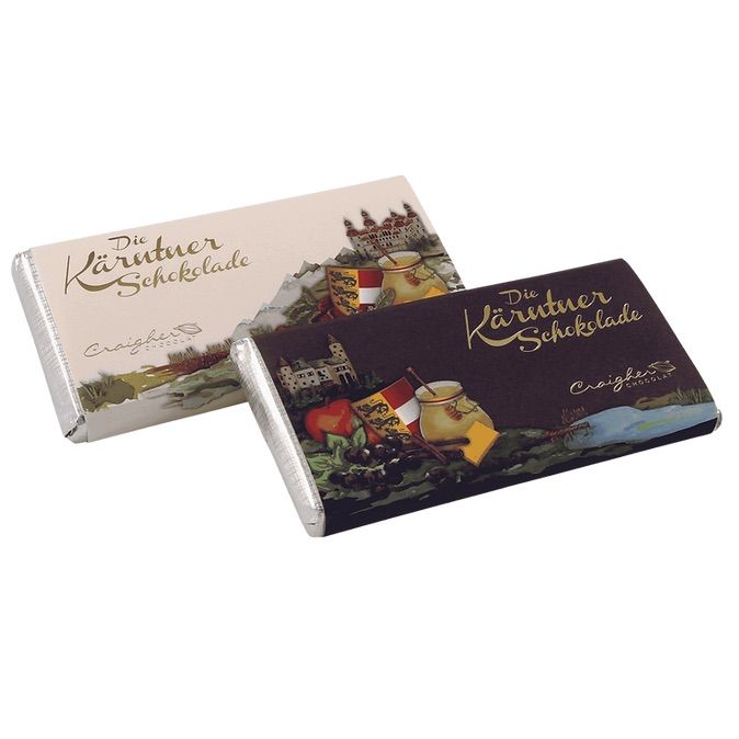 Two chocolate bars with the words 'Die Kärtner Schokolade' are shown. The background features a castle and other landmarks.