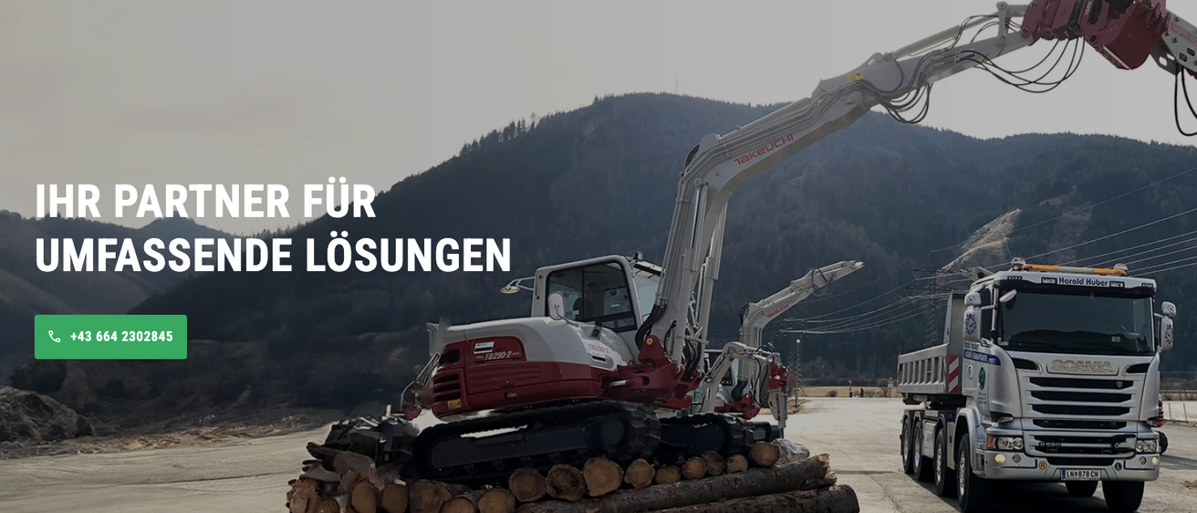 Ein rot-weißer Baumaschinenfahrzeug ist in Betrieb mit Holzstapeln in der Nähe. Im Hintergrund sind ein großer Berg und ein Lkw zu sehen.