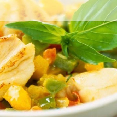 Ein Teller mit gekochtem Fisch und Gemüse, verziert mit grünen Blättern, steht auf einer weißen Oberfläche. Der Fisch hat eine goldbraune Kruste.