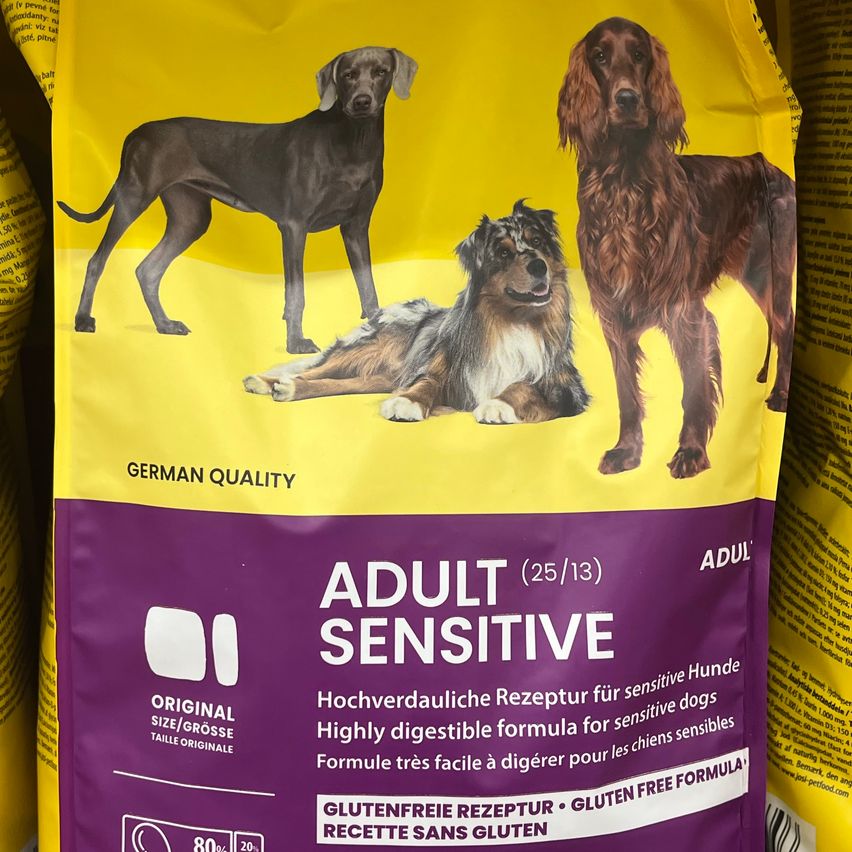 Packung deutsches Qualitätshundefutter für erwachsene Hunde. Es ist glutenfrei und leicht verdaulich, geeignet für empfindliche Hunde. Enthält drei Hunde in verschiedenen Posen auf gelbem Hintergrund.