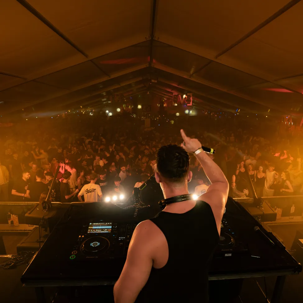 Ein Mann ist DJ bei einem Konzert mit einem Publikum vor ihm.