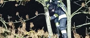 Ein Feuerwehrmann klettert nachts eine Leiter hoch. Er trägt die volle Ausrüstung.