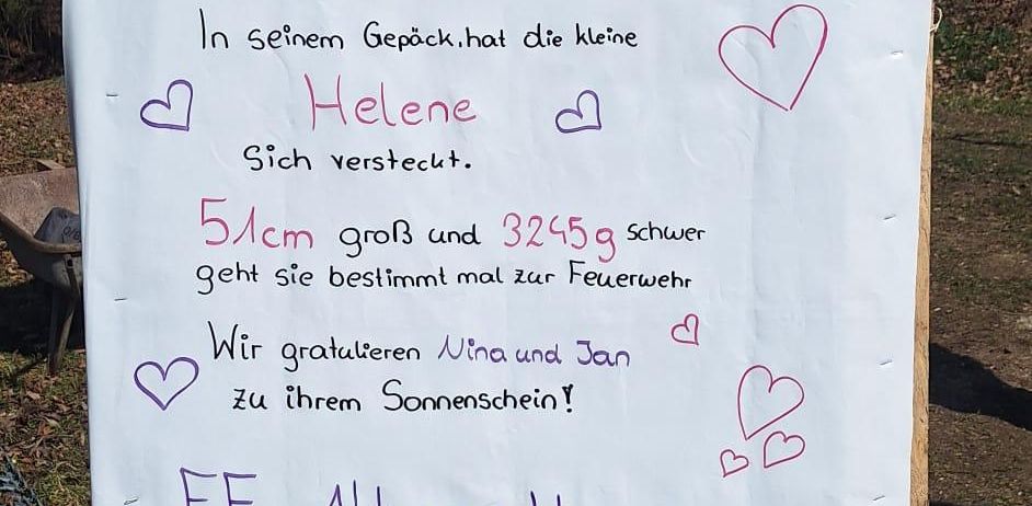 Ein Plakat mit Herzen und Text auf Deutsch, das den Feuerwehrmann Helene beschreibt. Der Plakat enthält eine Geburtstagsnachricht für Nina und Jan und erwähnt Helenes Größe und Gewicht.