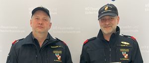 Zwei Männer in Uniform halten Auszeichnungen und stehen vor einem Hintergrund mit dem NO Feuerw Wehr Altenmarkt Logo.