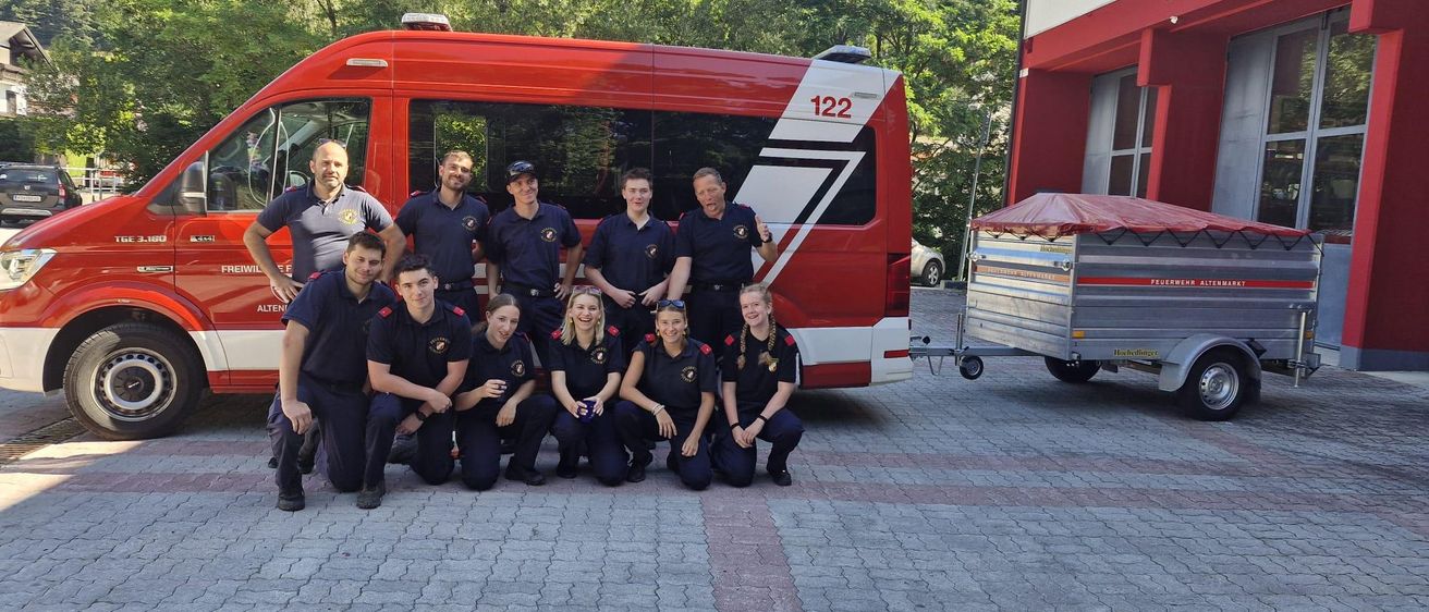 Eine Feuerwehrmannschaft posiert für ein Foto vor einem roten Feuerwehrwagen. Das Team trägt ihre Uniformen. Der Wagen hat die Nummer 122.