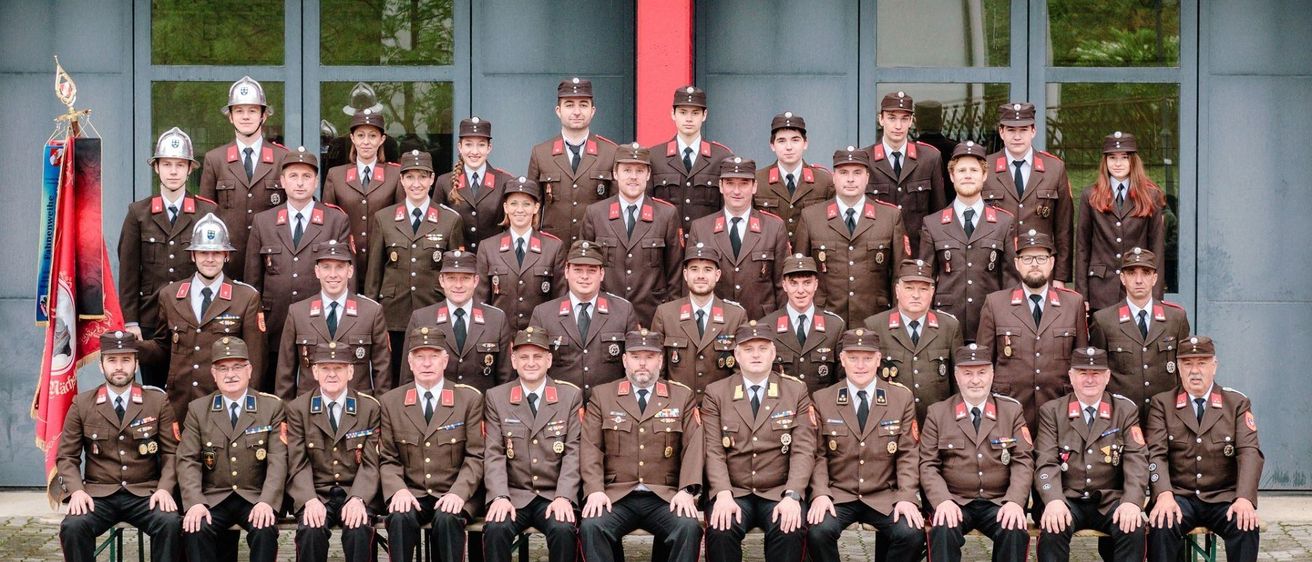 Eine Gruppe uniformierter Personen, wahrscheinlich eine Militär- oder Polizeieinheit, posiert für ein Foto vor einem modernen Gebäude mit Glaswänden.