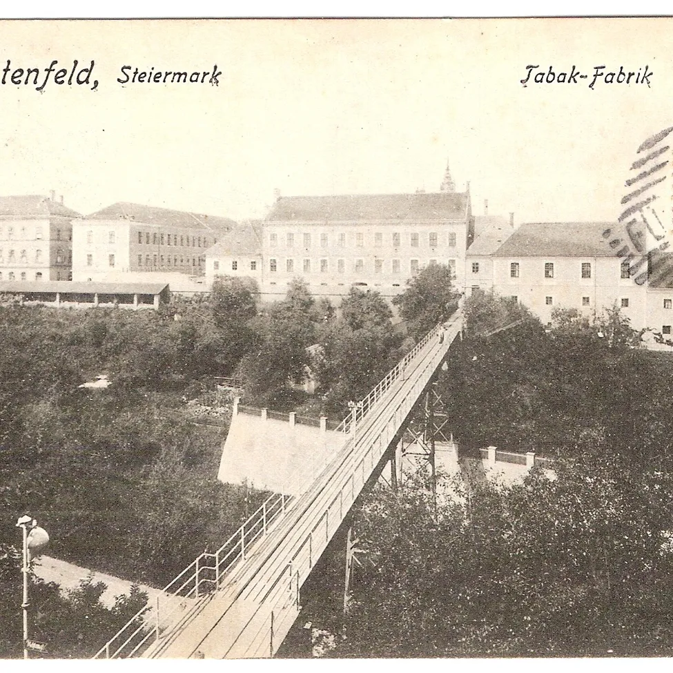 Ein altes Schwarz-Weiß-Foto einer Brücke über einem Tal mit Gebäuden im Hintergrund.