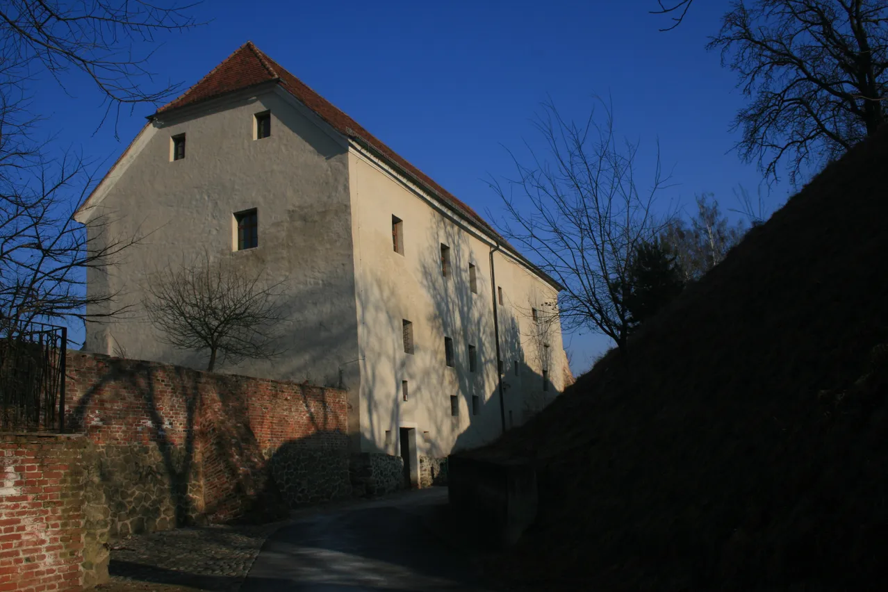 Ein großes Gebäude mit einem roten Dach und mehreren Fenstern befindet sich auf einem Hügel.