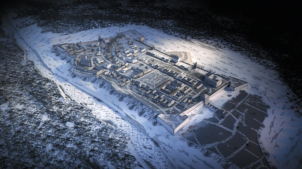 Eine Luftaufnahme einer mittelalterlichen Festung, die von Schnee umgeben ist. Die Festung hat einen großen zentralen Innenhof und mehrere Gebäude.