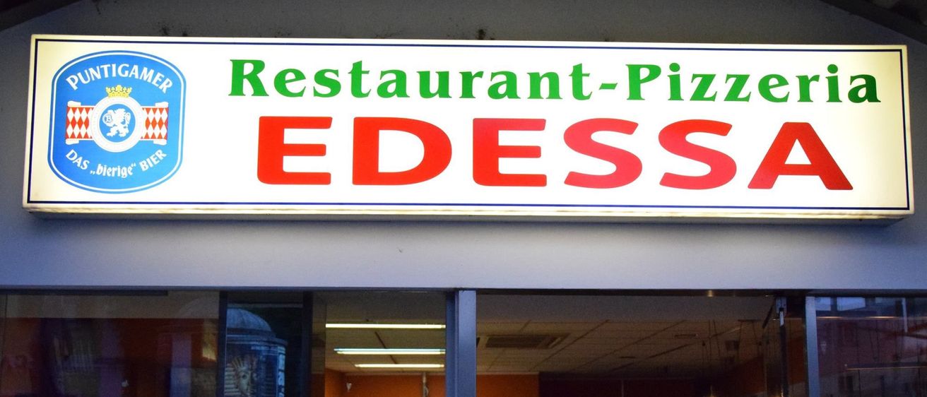 Der Eingang der Restaurant-Pizzeria Edessa. Eine Person steht an der Theke im Inneren.