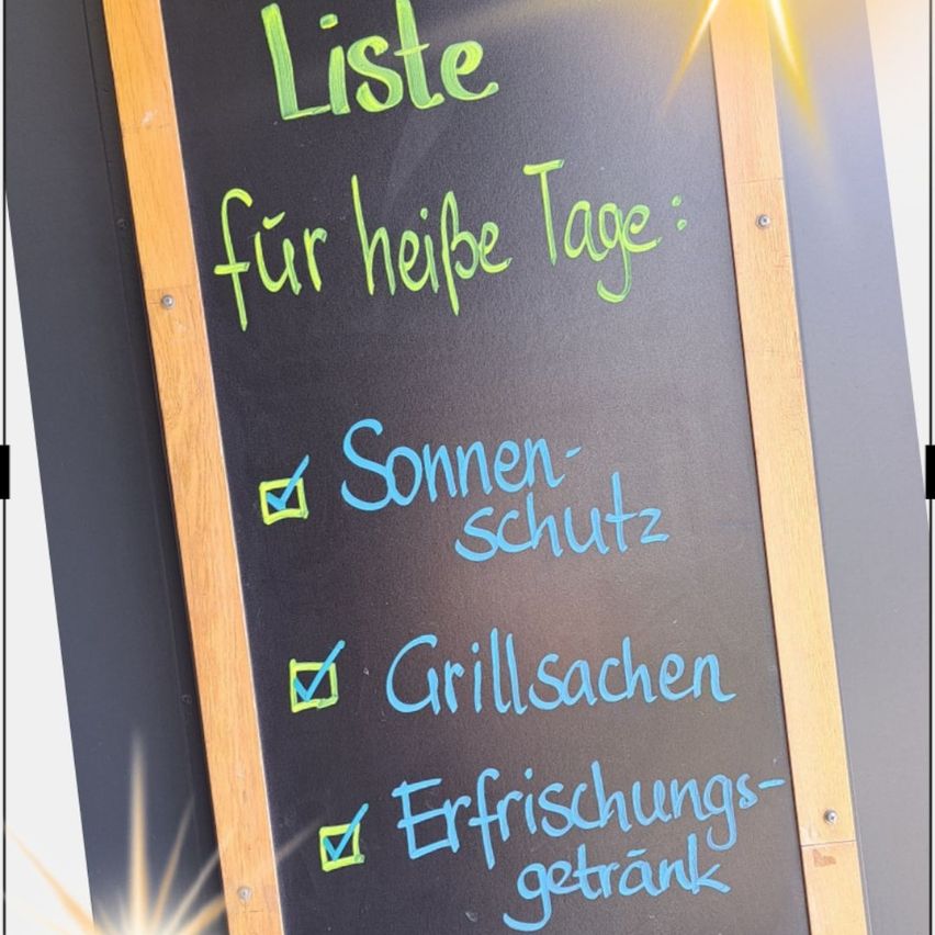 Ein Kreidetafel listet Artikel für heiße Tage auf, einschließlich Sonnenschutz, Grillsachen und Erfrischungsgetränke.